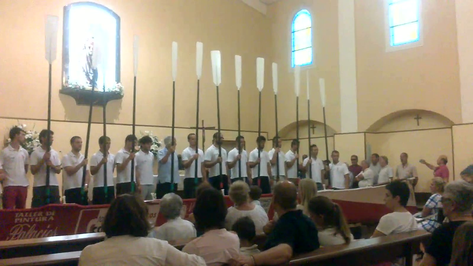 Remeros con los remos en alto junto a la trainera, en el interior de la iglesia